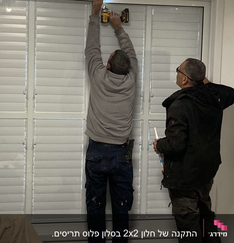 שני אנשים מתקינים תריסי אלומיניום עם מקדחה